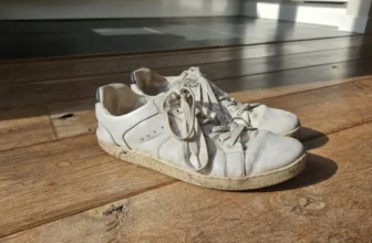 Flink gedragen witte Groundies barefoot sneakers op een houten vloer